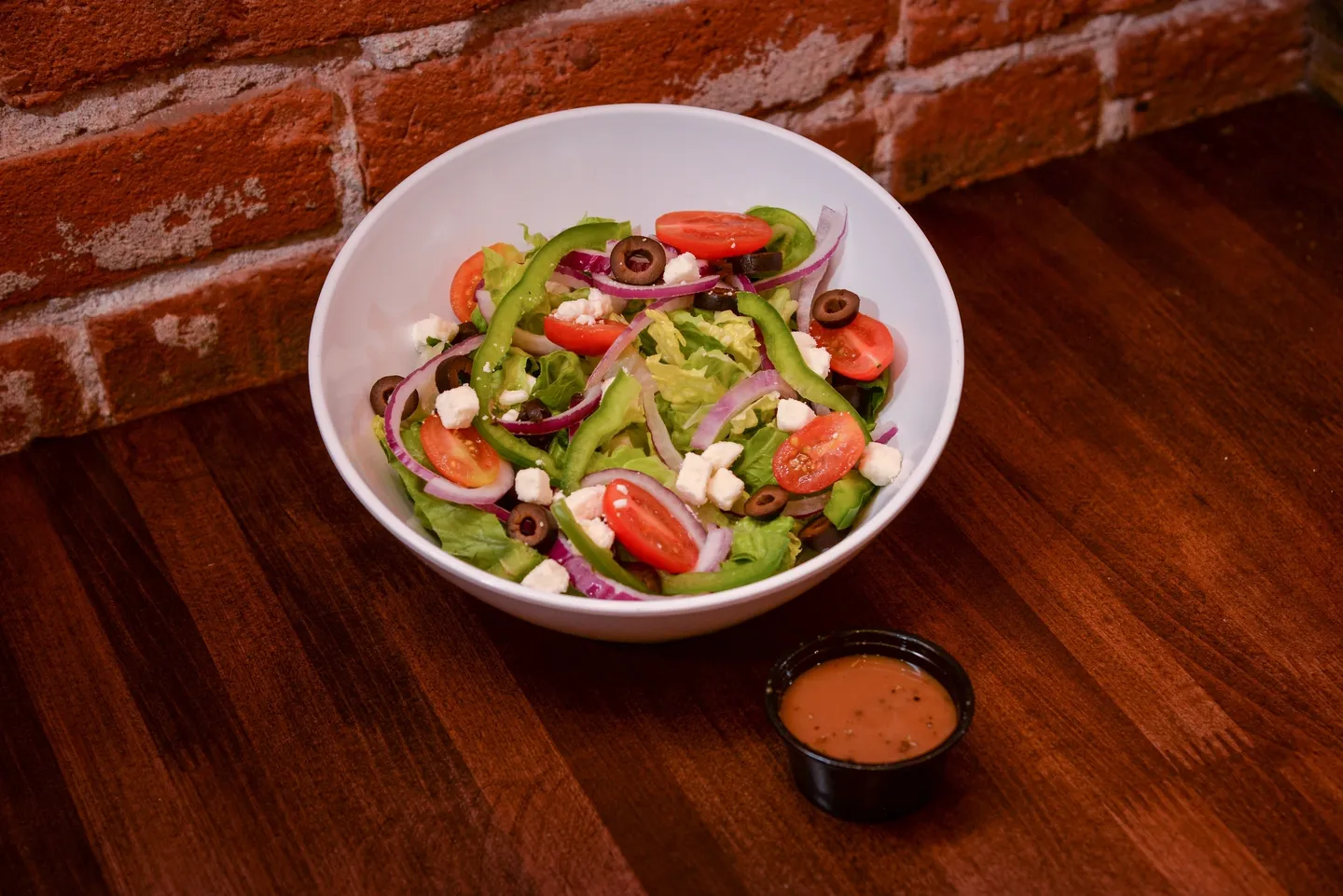 A bowl of salad with dressing on the side.