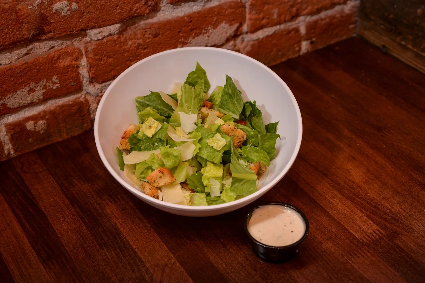 A bowl of salad and a small container of dip.