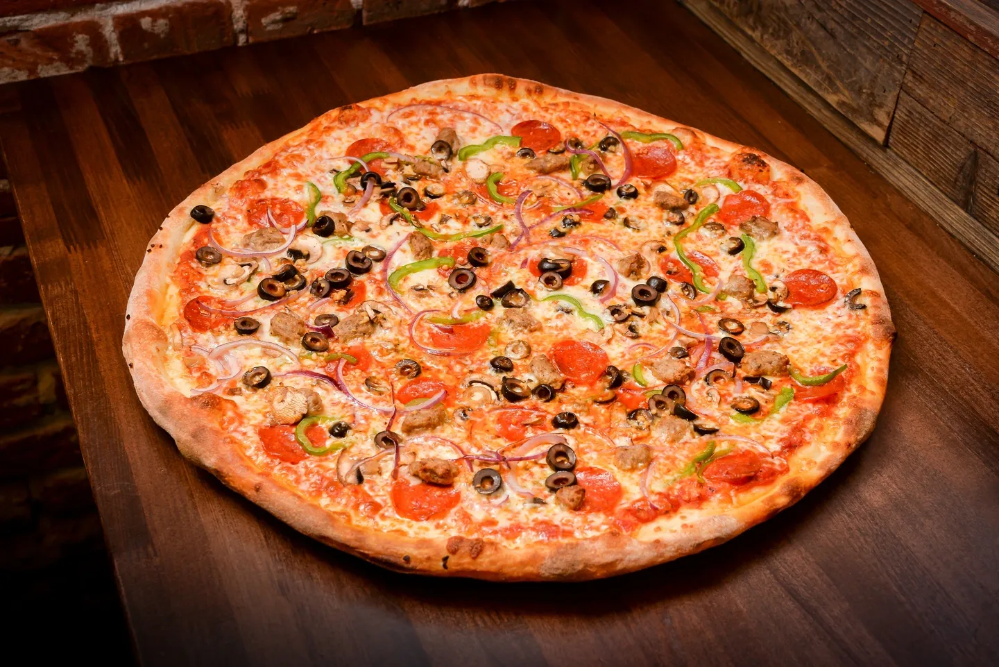 A pizza with olives, tomatoes and peppers on top of it.