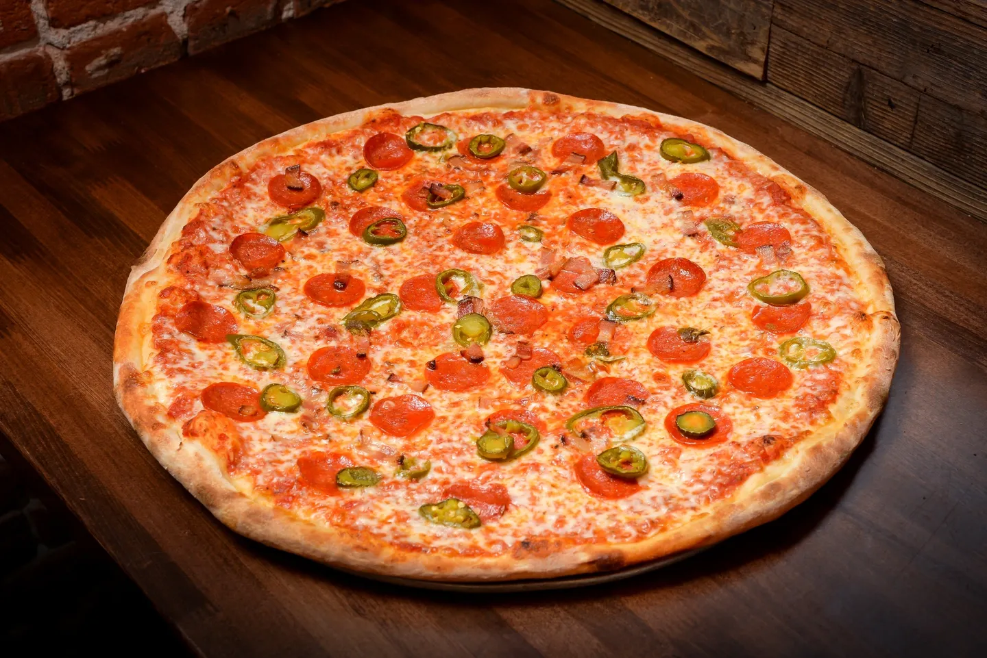 A pizza with tomatoes, peppers and jalapenos on it.