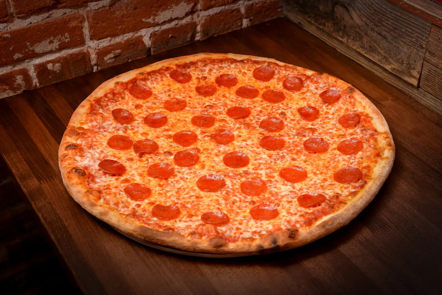 A pepperoni pizza sitting on top of a wooden table.