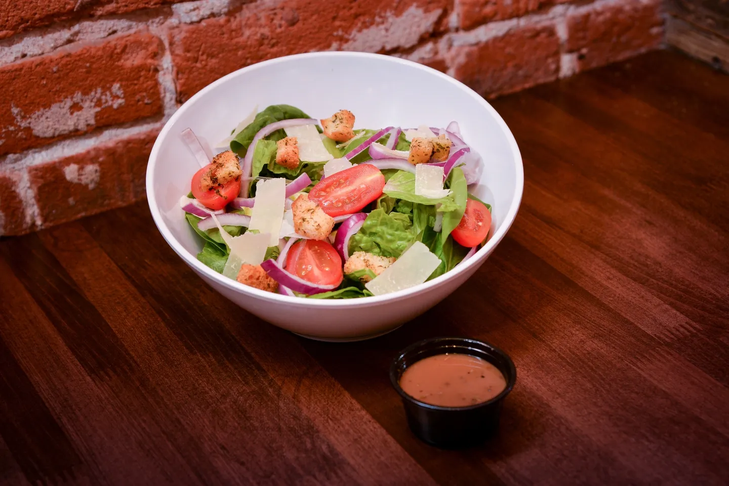 A bowl of salad with dressing on the side.